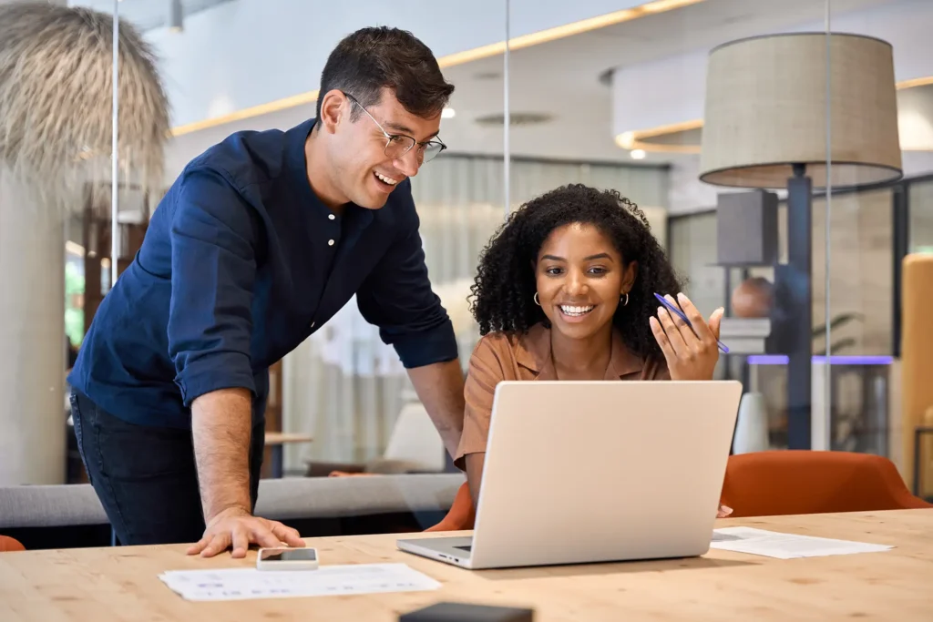 Two young busy diverse colleagues business people using laptop in modern office