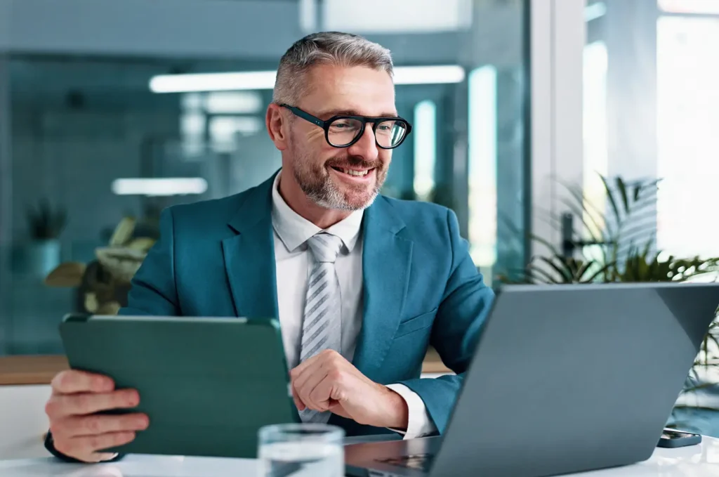 Mature, businessman and tablet with laptop in office, financial report